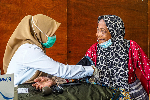 Indonesian health worker taking blood pressure